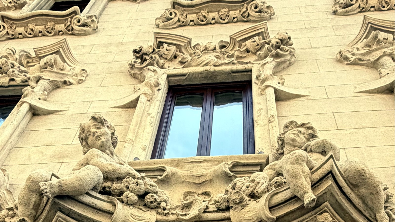 Facciata di un palazzo a Roma, affreschi e atlanti scolpiti in pietra attorno a una finestra